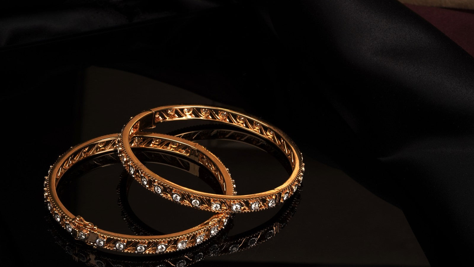 Two rose gold diamond bangles, the colour of the gold showing in warm light