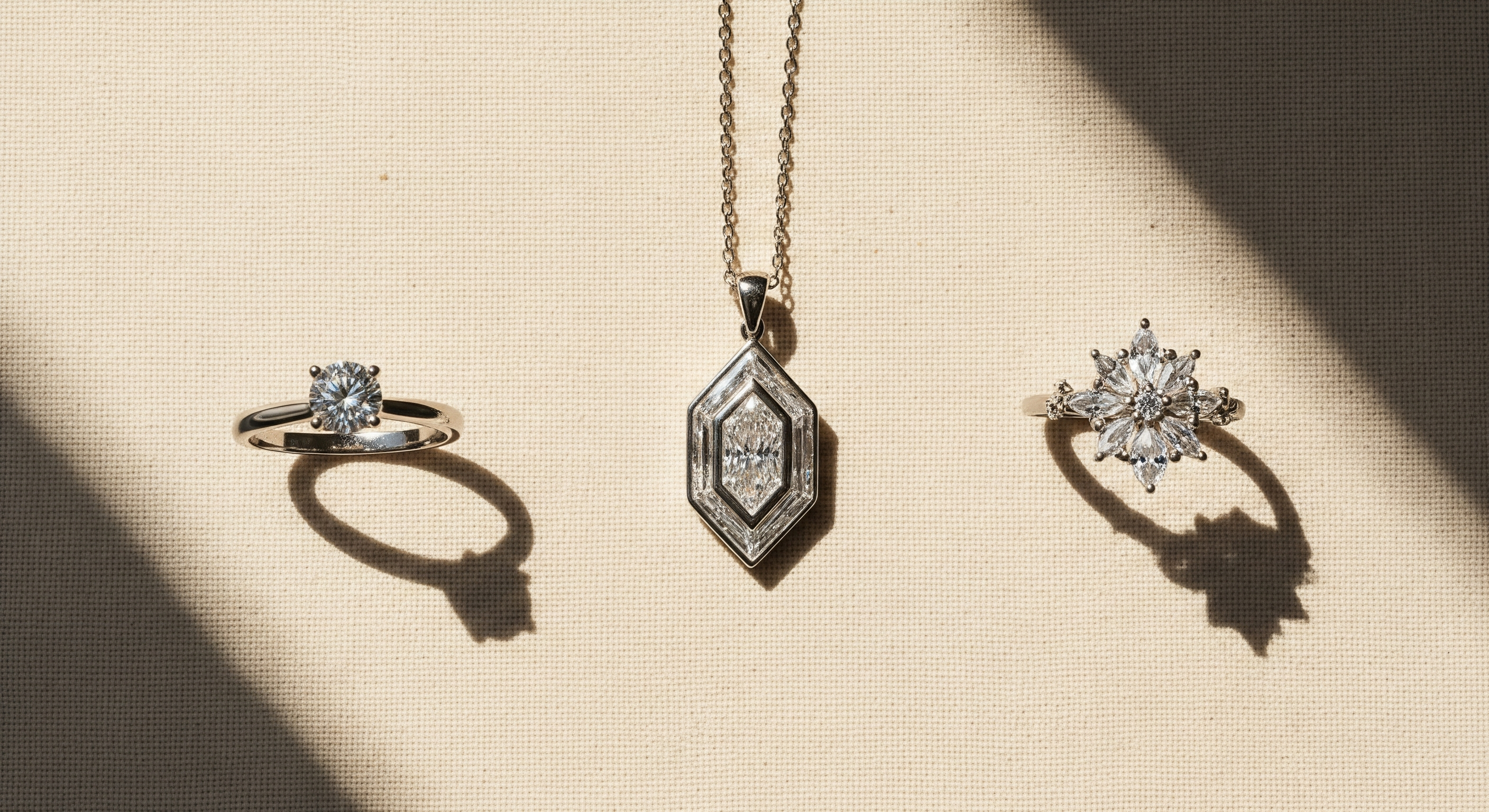 Three distinct lab-grown diamond jewellery pieces on cream linen: a classic solitaire ring, a bold geometric pendant, and a floral diamond ring