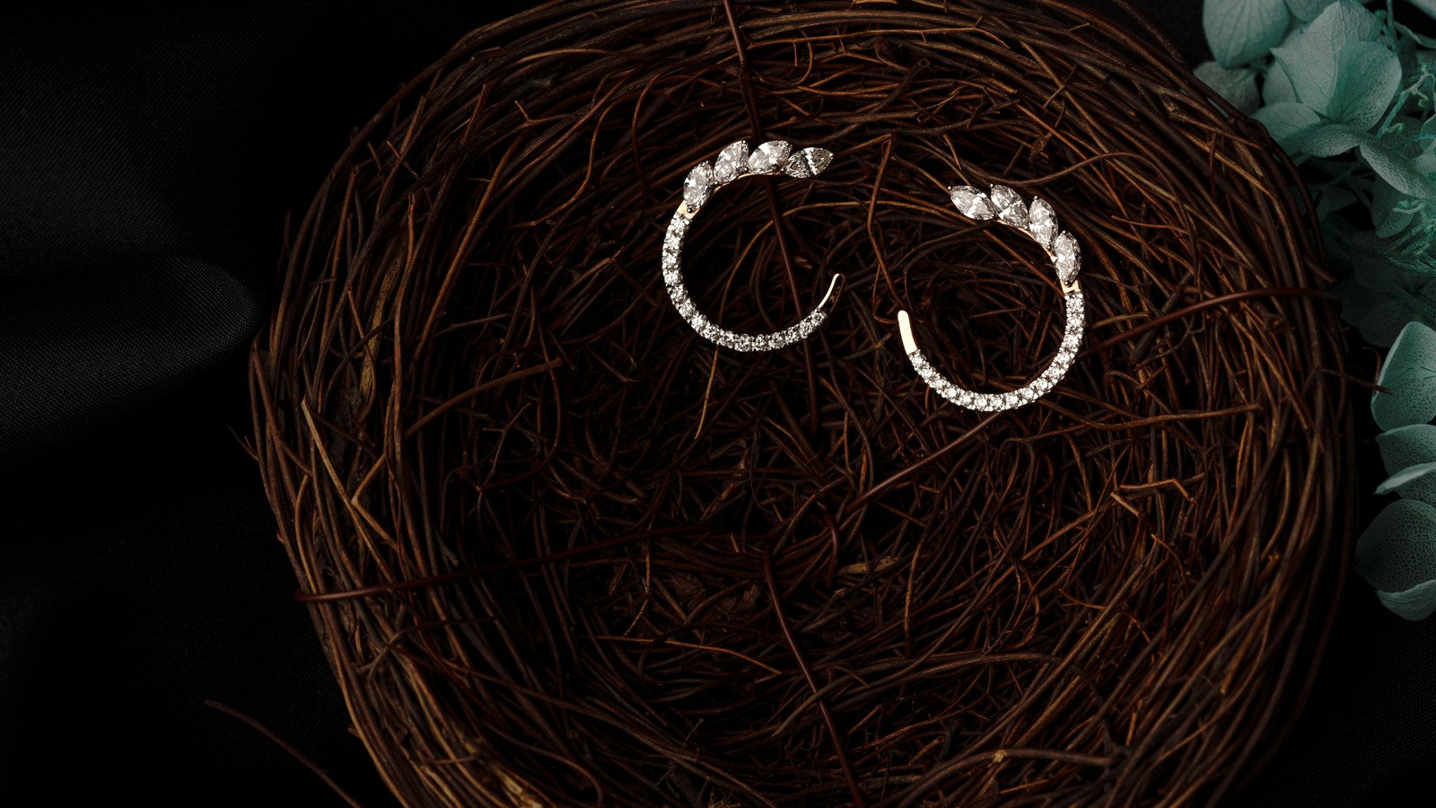 Pair of diamond hoop earrings resting in a woven nest