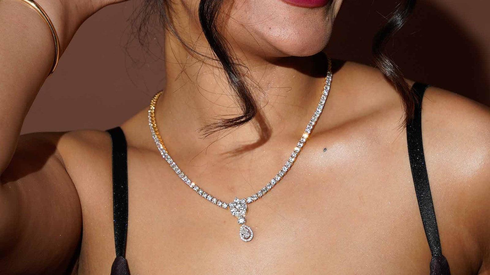 Woman laughing in a diamond necklace with a pear drop pendant at the collarbone