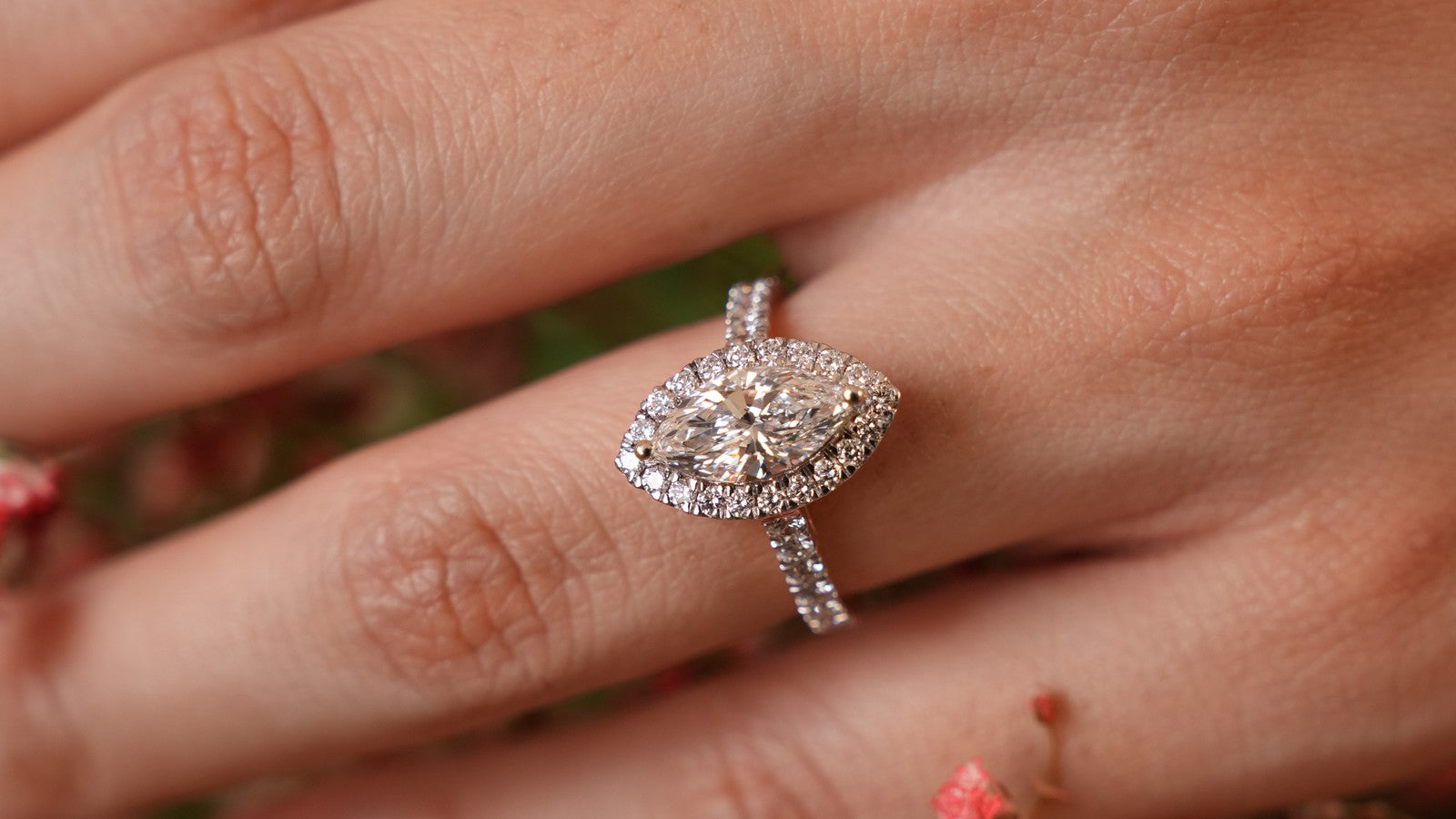 Marquise lab grown diamond ring in a halo, worn on the hand over pink flowers