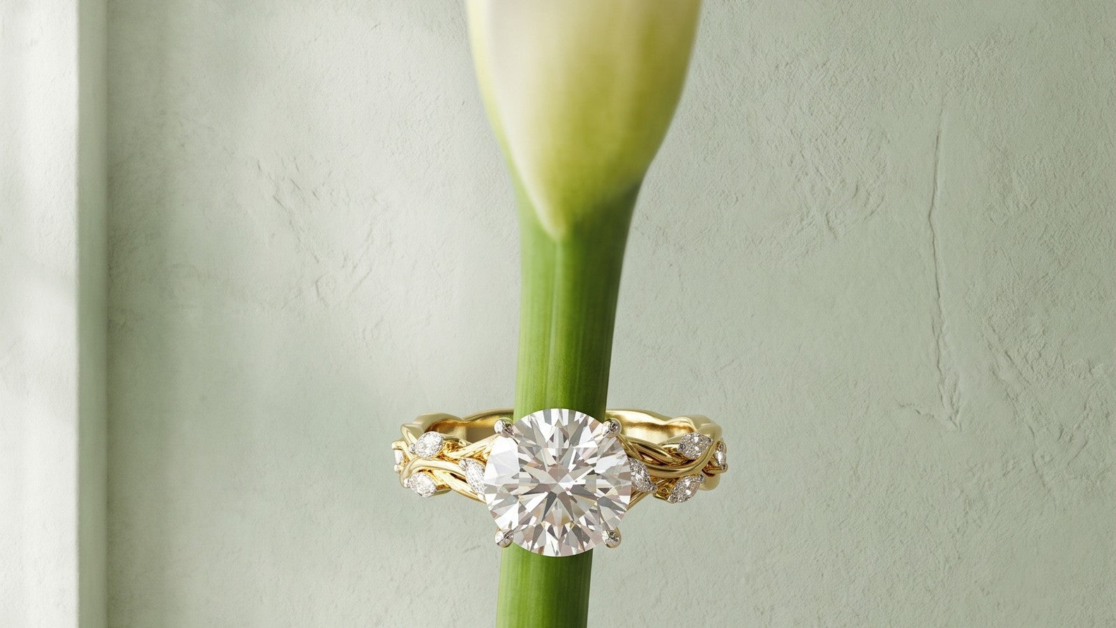 A diamond ring resting on the stem of a white calla lily