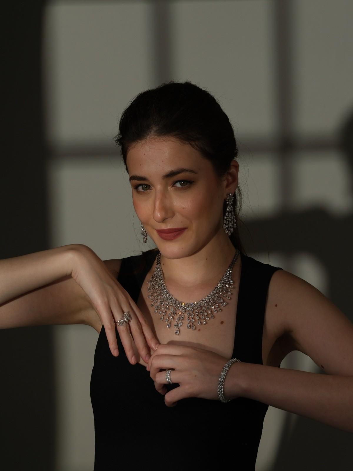 Woman wearing a diamond necklace set with matching diamond earrings, bracelet and rings in an elegant black dress